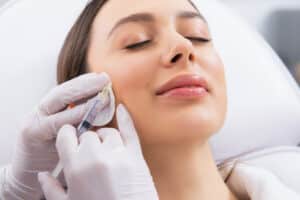 Happy young woman getting Botox injections to prevent future wrinkles from forming