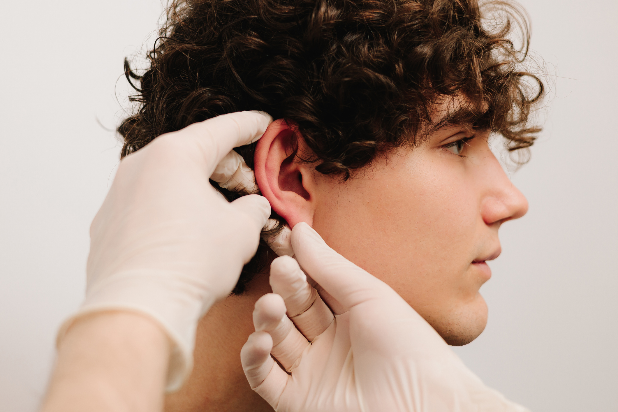 Plastic surgeon examining a patient's ears before otoplasty consultation.