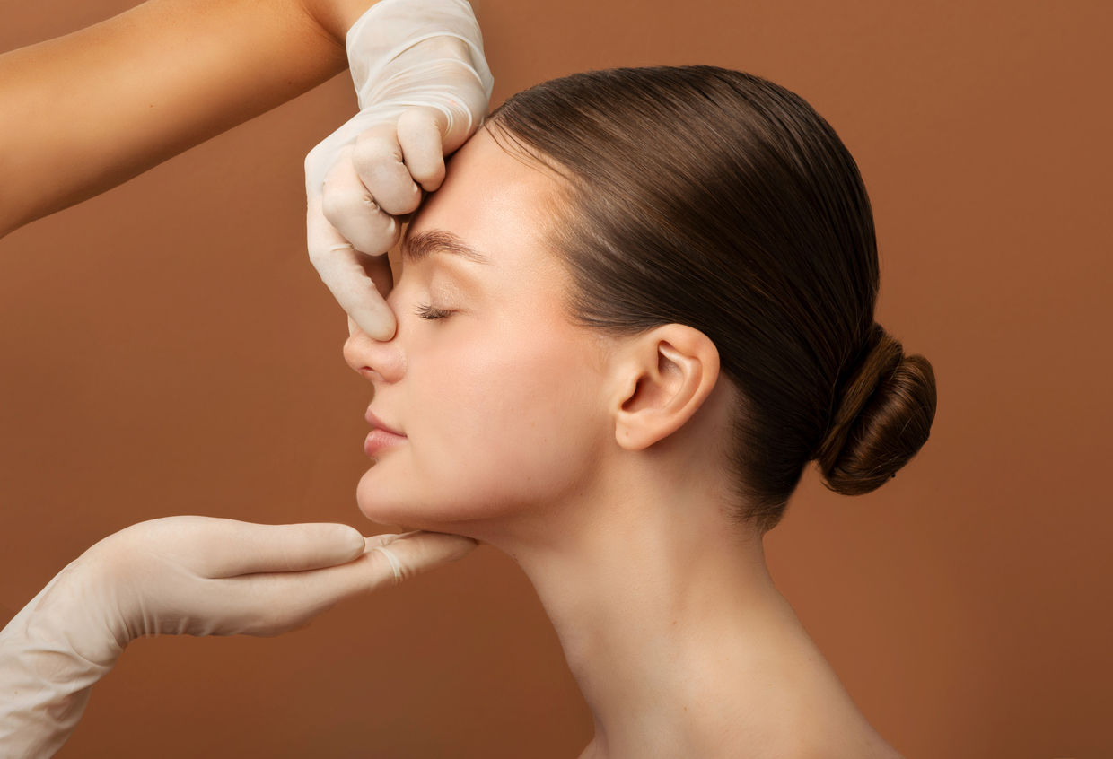 Surgeon examining a woman’s nose before rhinoplasty.